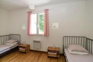 a bedroom with two beds and a window with pink curtains at L'ECRIN DU LAC - L'Ortencia in Mazamet