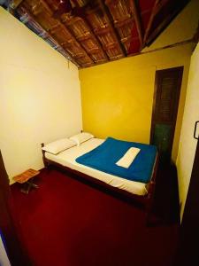 a small bedroom with a bed with a blue blanket at Oryza wayanad in Kalpetta