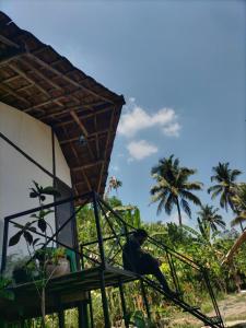 a man sitting on a porch of a house with palm trees at Oryza wayanad in Kalpetta