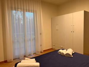 een slaapkamer met een bed met handdoeken en een groot raam bij Residence Il Pantheon - Artemide in Marina di Fuscaldo