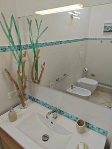 a bathroom with a sink and a toilet and a mirror at La Casa Di Irene in Riotorto
