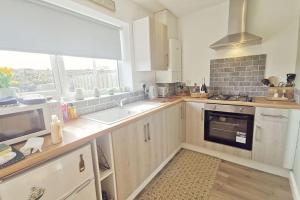 a kitchen with white cabinets and a large window at WILLOW SNUG - Trearddur Bay COSY apartment in Trearddur