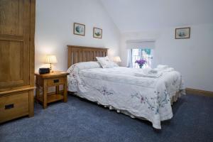ein Schlafzimmer mit einem Bett und einem Tisch mit einem Nachttisch in der Unterkunft Towy Cottage Cenarth in Cenarth