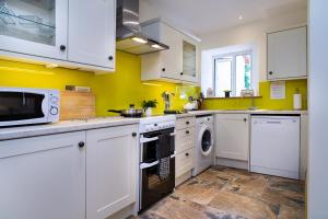 Cenarth的住宿－Towy Cottage Cenarth，厨房配有白色橱柜、洗衣机和烘干机