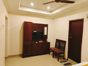 - un salon avec une télévision et une chaise dans l'établissement Hotel Harish, à Rameswaram