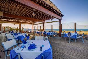 a restaurant with blue tables and chairs and the ocean at TUI Magic Life Candia Maris - Adults Only in Amoudara Herakliou