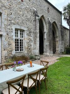 a table with chairs in front of a stone building at ABBAYE DE BLANCHELANDE in Neufmesnil
