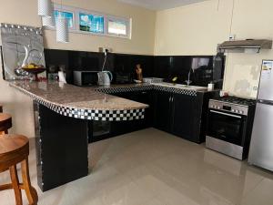 a kitchen with black cabinets and a granite counter top at Blue sea in Baie du Cap