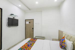 a bedroom with a bed and a tv on a wall at FabHotel Angeethi in Aurangabad
