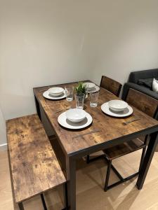 a wooden table with plates and glasses on it at Luxury Apartment - 2 minute walk from the O2 Arena in London