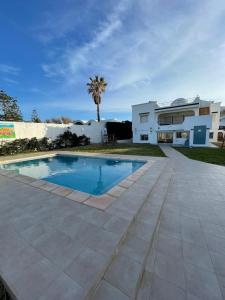 a villa with a swimming pool in front of a house at Dar Riahi Ras Jbal in Raʼs al Jabal