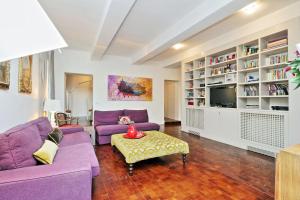 sala de estar con sofás morados y TV en Residenza Torre Vecchiarelli - apt 4, en Roma