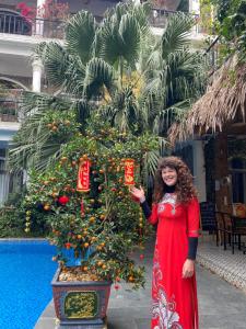 a woman in a red dress standing next to a christmas tree at Tam Coc Full House Homestay in Ninh Binh