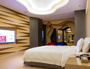 a bedroom with a large bed and a flat screen tv at All-Ur Boutique Motel - Hualian Branch in Ji'an