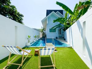 einen Hinterhof mit zwei Stühlen und einem Pool in der Unterkunft White Castle in Panwa Beach