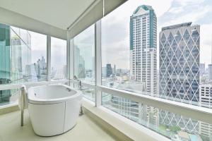 a bathroom with a bath tub and large windows at Eastin Grand Hotel Sathorn in Bangkok