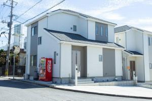 a white house with a soda machine in front of it at シンプルでおしゃれなインテリアが光る4LDKの一軒家まるまる貸し切り！最大12名まで宿泊可能！ in Tokeshi