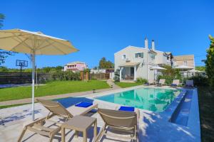 Una piscina con sillas y una sombrilla al lado de una casa. en Villa Teresa, en Rodas