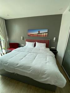 a large white bed in a bedroom with a red chair at 8 Hotel & cafe in Bangkok