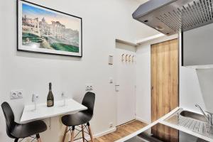 a kitchen with white walls and black chairs and a table at Le cosy saint clair in Caluire-et-Cuire