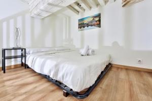 two beds in a room with white walls and wooden floors at Le cosy saint clair in Caluire-et-Cuire