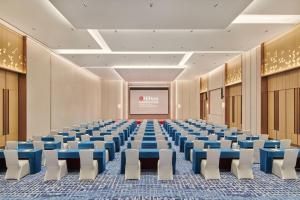 una sala de conferencias vacía con sillas azules y una pantalla en Hilton Garden Inn Shenzhen Guangming, en Shenzhen