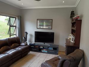 a living room with two leather couches and a flat screen tv at Wild Fig Wild Life Estate White River in White River