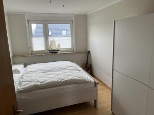 ein weißes Schlafzimmer mit einem Bett und zwei Fenstern in der Unterkunft Nordseekrabbe in Holtgast