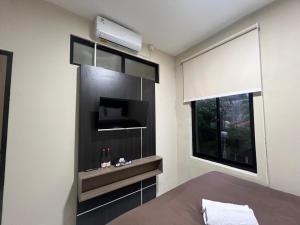 - une chambre avec une télévision à écran plat et une fenêtre dans l'établissement Brenn Hotel Semarang Mitra Reddoorz, à Semarang