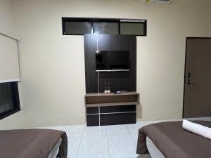 une chambre avec deux lits et une télévision à écran plat dans l'établissement Brenn Hotel Semarang Mitra Reddoorz, à Semarang 50 autres photos
