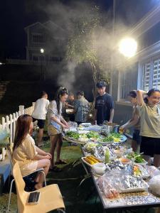 a group of people standing around a table with food at Villa 028 - Villa Novaworld Phan Thiet View Biển - 4BR - 3 Toilet in Phan Thiet