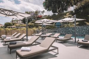 een rij ligstoelen en parasols naast een zwembad bij VILLA QUINTA TORRINHA Rooms in Funchal