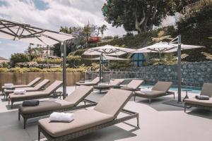 a row of lounge chairs and umbrellas next to a pool at VILLA QUINTA TORRINHA Rooms in Funchal