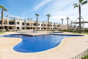 a large swimming pool in front of a building with palm trees at Playa Elisa Bay app 411 in Pilar de la Horadada