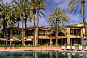 a resort with palm trees and a swimming pool at Huerto del Cura in Elche