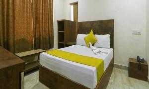 ein Schlafzimmer mit einem Bett mit einer gelben und weißen Decke in der Unterkunft FabHotel Rama Inn I in Gwalior