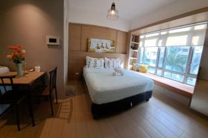 a bedroom with a bed and a table and a window at Lovely Condo near NAIA T3 in Manila