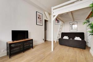 a living room with a couch and a flat screen tv at Cosy home with terrace near Canal Saint-Martin in Paris