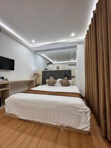 1 dormitorio con 1 cama blanca grande y TV en Win Hotel CAFE & SPA, en Vientiane
