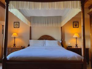 a bedroom with a canopy bed with two night stands at Le Relais de Saint-Preuil, The Originals Relais (Relais du Silence) in Saint-Preuil