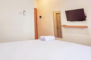 a bedroom with a white bed with a tv on the wall at Hotel Buana Express RedPartner in Bojonegoro