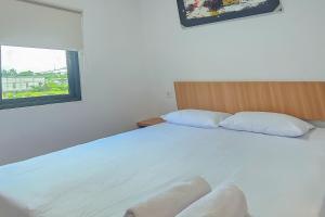 una camera da letto con un grande letto bianco e una finestra di Hotel Buana Express Mitra RedDoorz a Bojonegoro