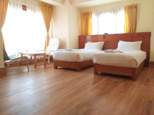 um quarto com 2 camas, uma mesa e janelas em Hotal Khuruu Khuruu em Pajo