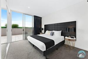 um quarto com uma cama grande e uma varanda em 18luxury apt in heart of chatswood free parking em Sidney