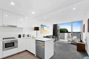 uma cozinha com electrodomésticos brancos e uma sala de estar em 18luxury apt in heart of chatswood free parking em Sidney