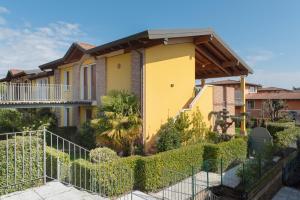 a yellow house with a fence in front of it at Residence Garda Sole 3-69 by Wonderful Italy in Padenghe sul Garda