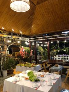 a dining room with white tables and flowers on them at Đỗ Gia Bảo Villa in Da Lat