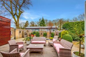 a patio with wicker furniture and a table and chairs at Chalet Louis met riante tuin en 3 slaapkamer 6p in Putten