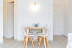 stół z 4 białymi krzesłami i stół z talerzem w obiekcie Ca Na Mercè w mieście Cala Morell
