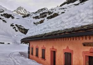 un edificio con una montaña cubierta de nieve en el fondo en Rifugio Casa di Caccia en Noasca
